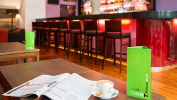 A bar area with a menu stand, a table with a menu, and a cup of coffee.