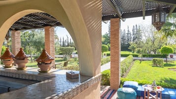 Un espace extérieur aménagé, abrité et doté de pots en terre cuite, d’un sol carrelé et d’une vue sur un jardin bien entretenu.