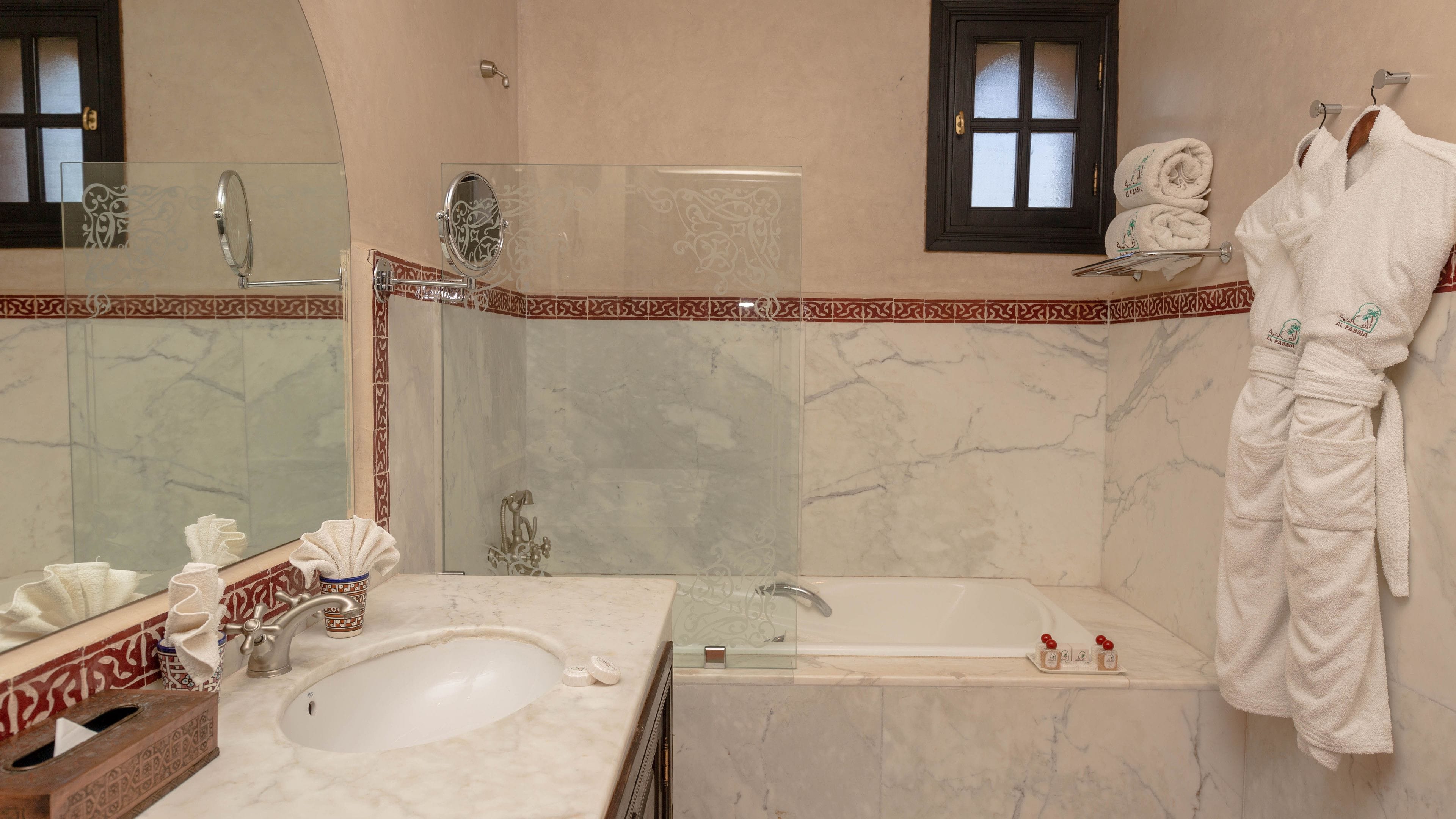 A bathroom with a marble sink, a glass-enclosed shower, a bathtub, and a large mirror.