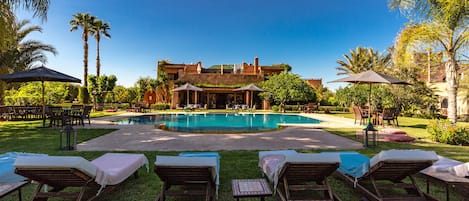 Relax by the serene pool surrounded by lush greenery and lounge chairs.