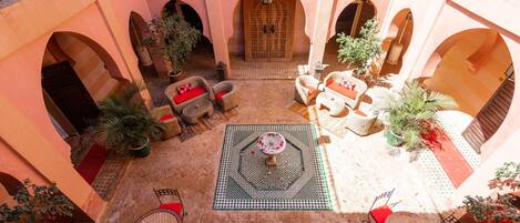 An open courtyard with a central fountain, seating areas, and potted plants.