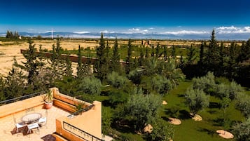Um terraço com mesa e cadeiras, rodeado por árvores e vista para montanhas cobertas de neve.