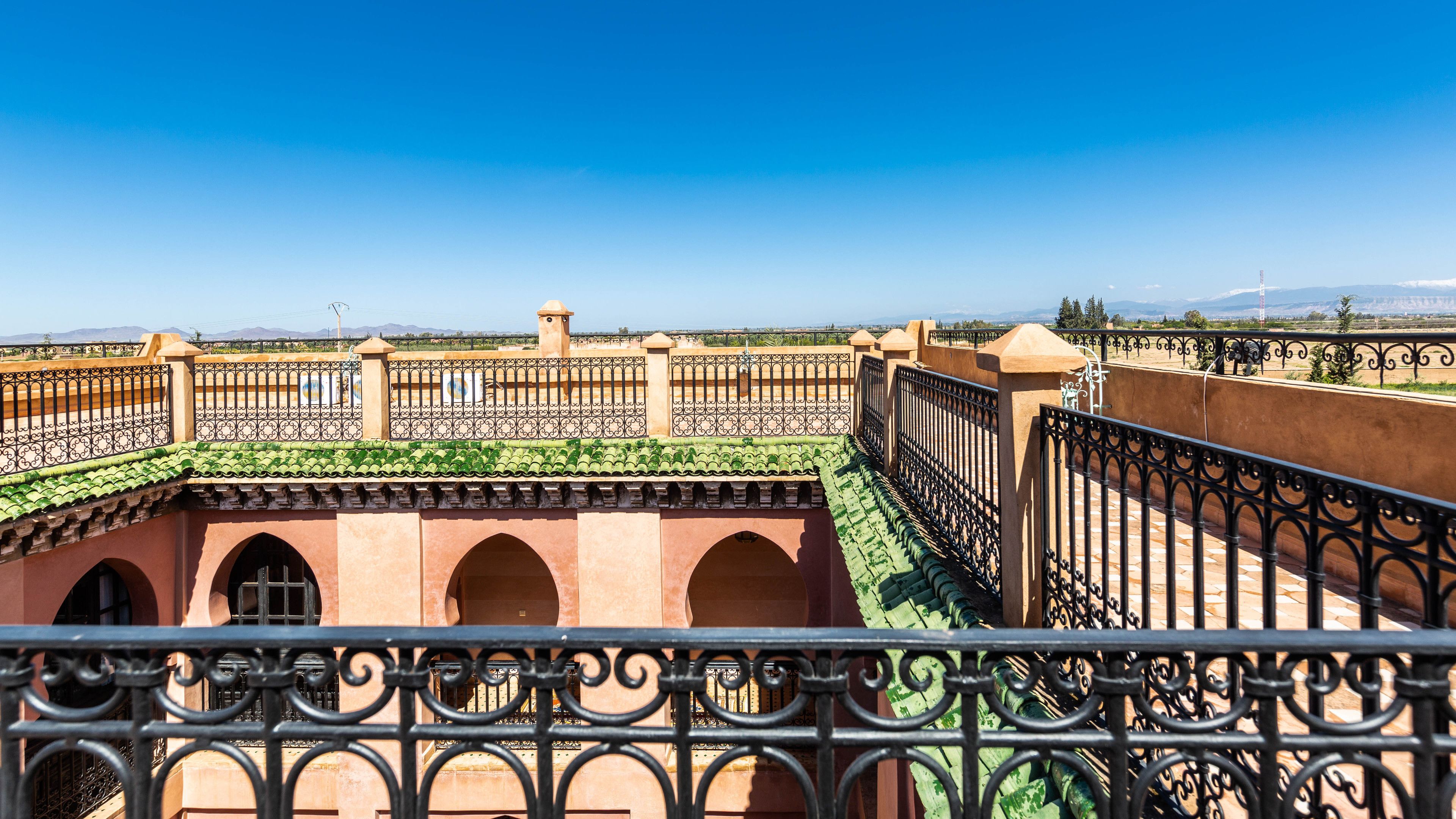 A courtyard with a tiled roof, arches, and a metal fence.