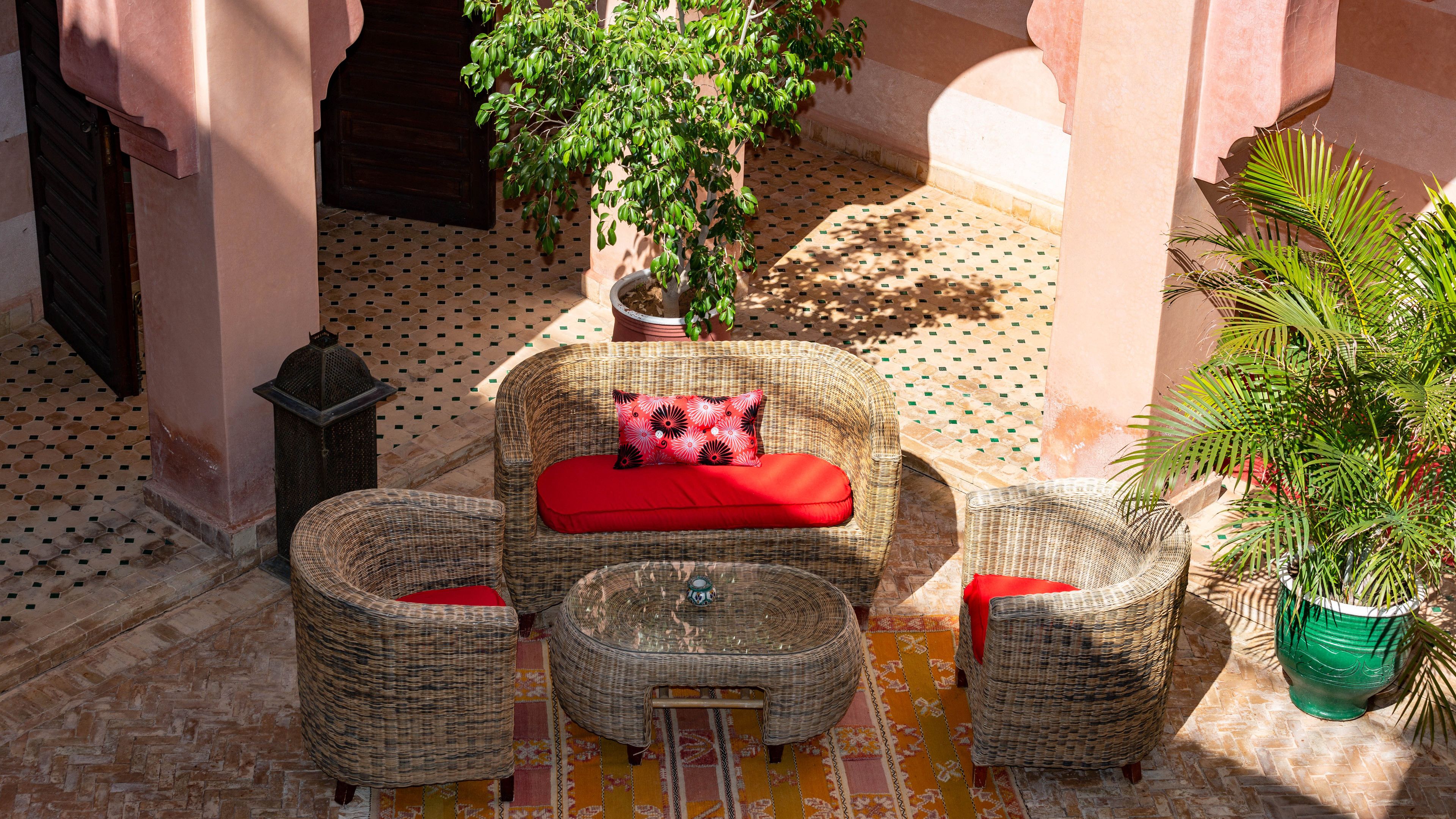 A cozy outdoor seating area with wicker furniture and a patterned rug.