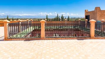 A courtyard with a wrought iron fence, a tiled floor, and a view of snow-capped mountains in the background.