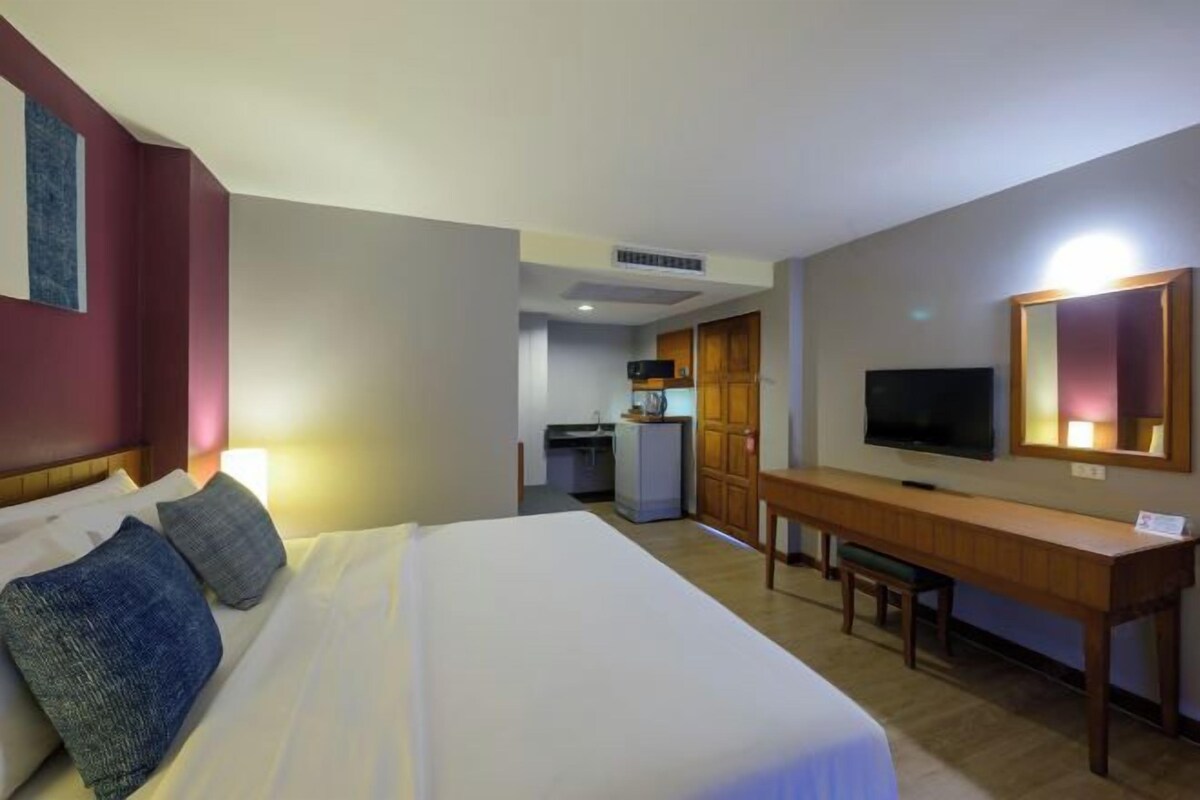 Una camera d'albergo con un letto, una scrivania, una televisione e angolo cottura.