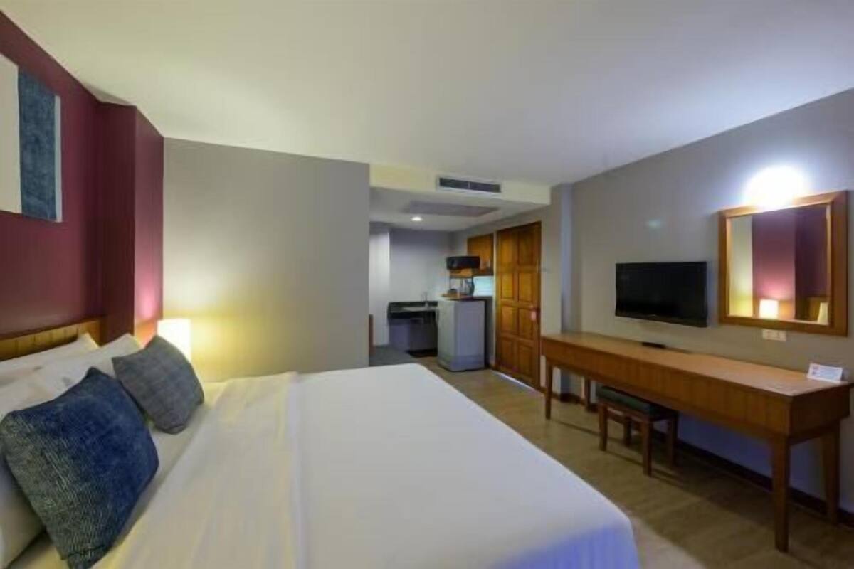 Ein Hotelzimmer mit Bett, Schreibtisch, Fernseher und einer Küchenzeile.