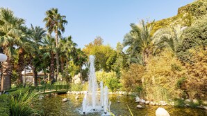 A tranquil garden with a central water feature, surrounded by lush greenery and palm trees. - LABRANDA Alantur Resort - All Inclusive (Alanya)