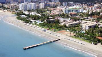 Vista aérea de una ciudad costera con una playa, un muelle y edificios circundantes.