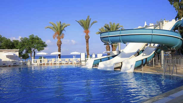 A water park with a large pool, slides, palm trees, and lounge chairs. - LABRANDA Alantur Resort - All Inclusive (Alanya)