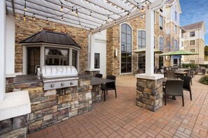 Une terrasse extérieure avec un barbecue en pierre et un espace salon.