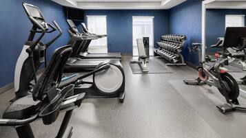 A gym with treadmills, elliptical machines, and a weight bench.