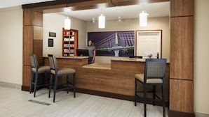 A reception area with a wooden reception desk, bar stools, a bookshelf, and a framed picture of a bridge. - Staybridge Suites Durham/Chapel Hill by IHG (Durham)