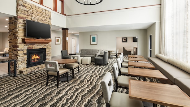 A spacious lobby with a stone fireplace, comfortable seating, and a large chandelier. - Staybridge Suites Durham/Chapel Hill by IHG (Durham)