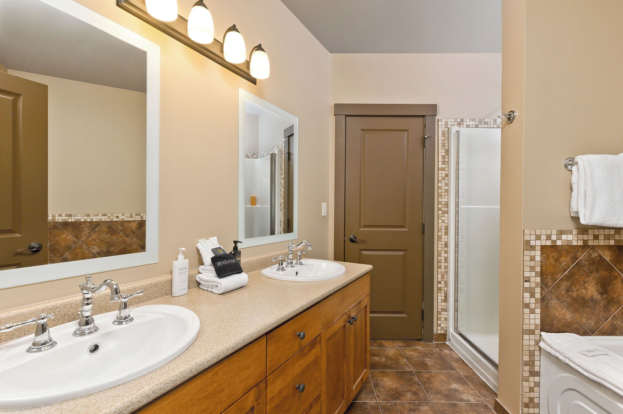 A bathroom with two sinks, a large mirror, and a shower.