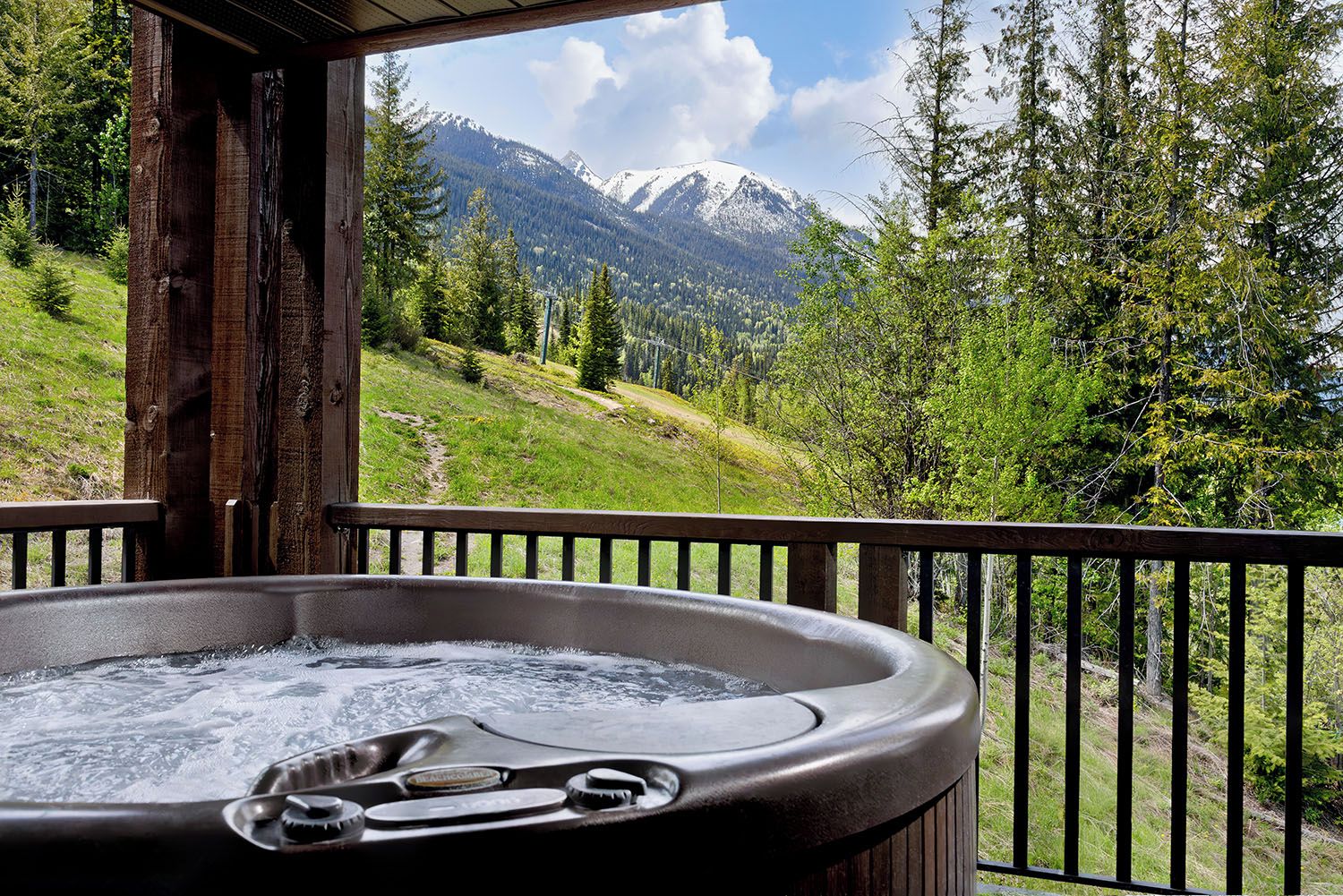 A hot tub on a wooden deck with a mountain view.