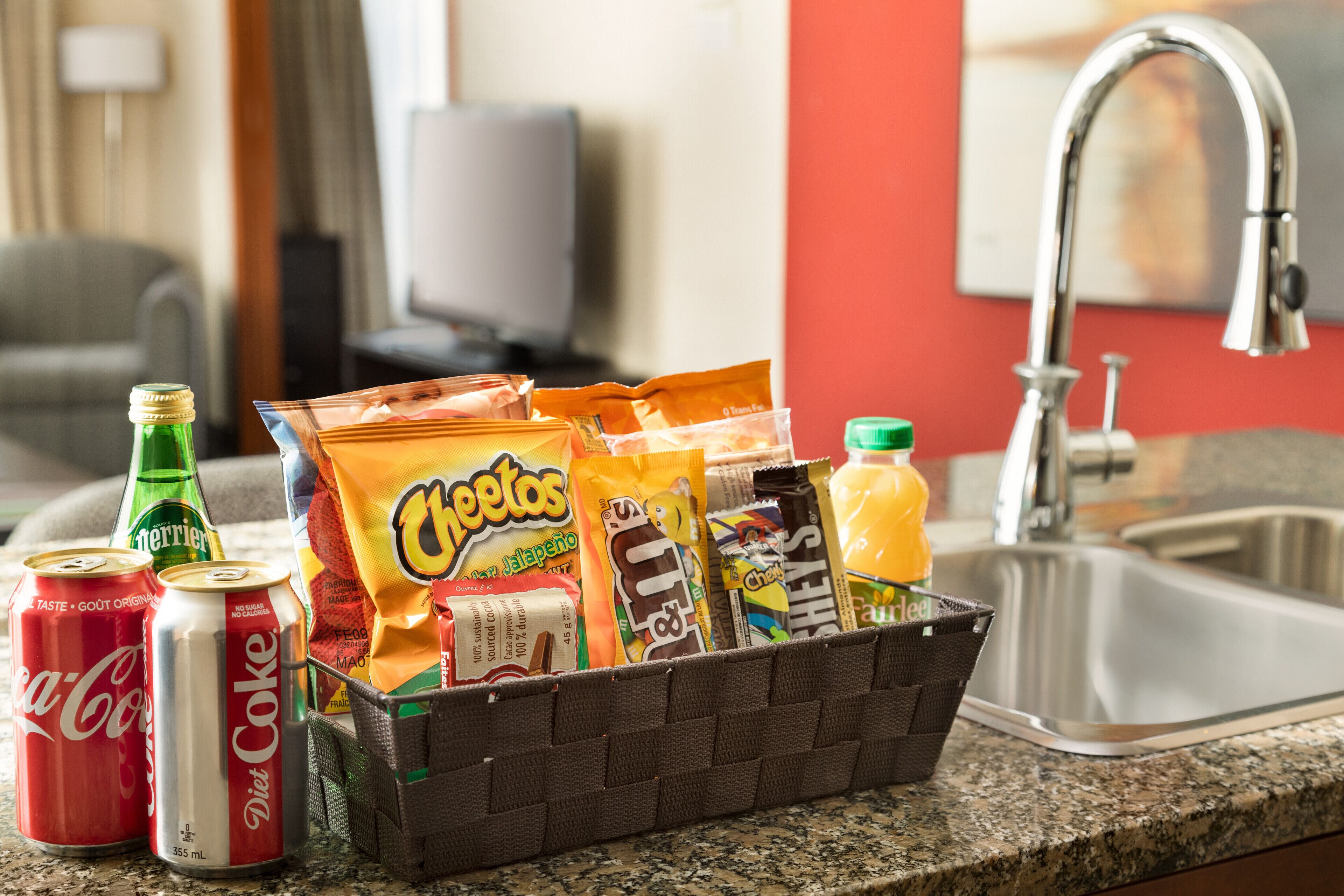 A snack basket on a kitchen counter with various snacks and drinks.