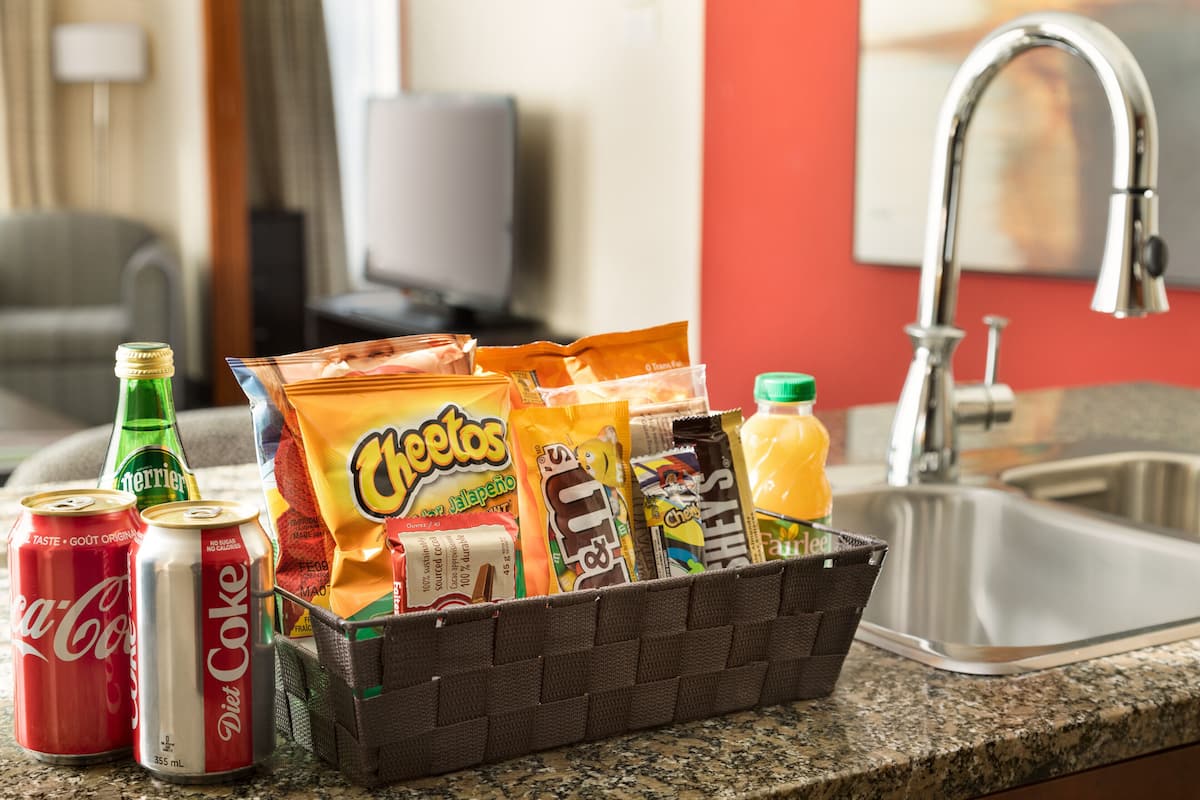 A snack basket on a kitchen counter with various snacks and drinks.