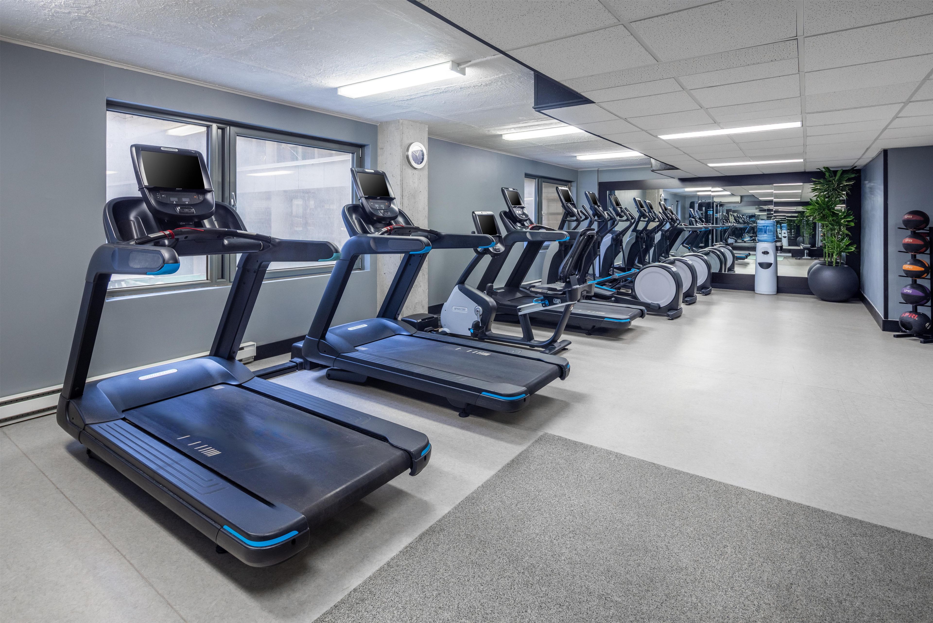 A gym with multiple treadmills, exercise balls, and a water dispenser.