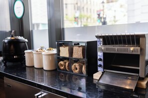 A breakfast bar with a coffee machine, a bread display, and a toaster. - Embassy Suites Montréal by Hilton (Montreal)