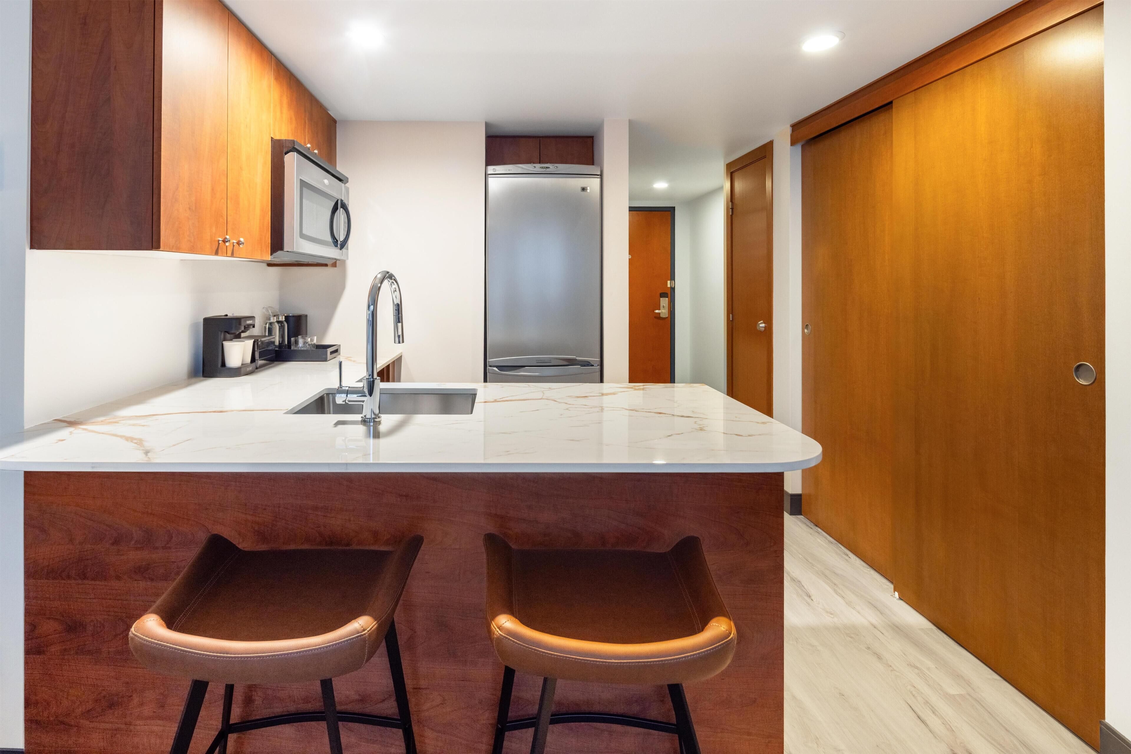 A modern kitchen with a marble countertop, stainless steel appliances, and wooden cabinets.