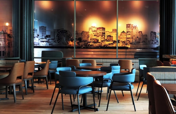 A modern restaurant with a view of a city skyline through large windows.