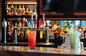 A bar with a variety of liquor bottles and a large TV screen in the background.