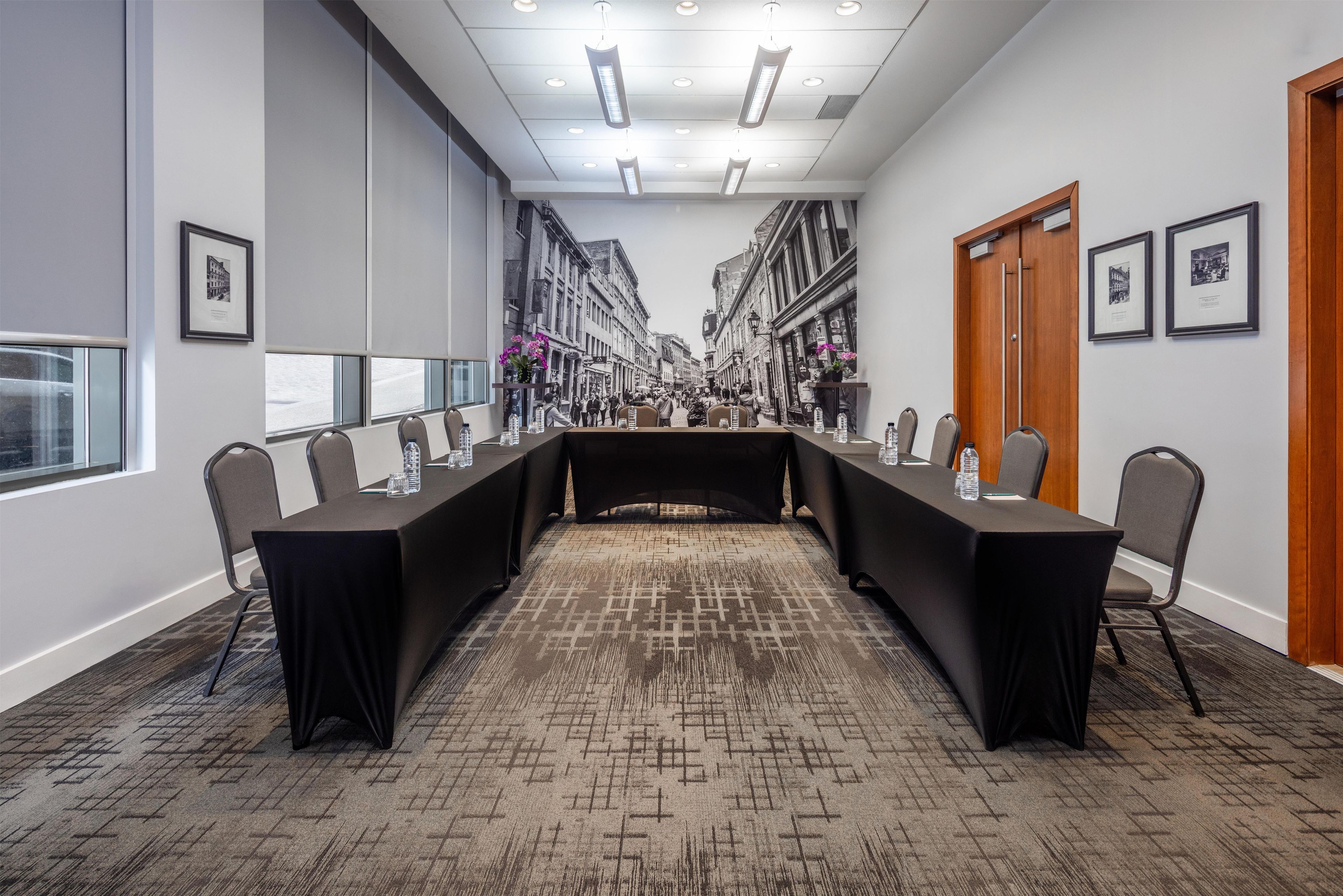 Uma sala de conferência com uma mesa comprida, cadeiras e quadros nas paredes.
