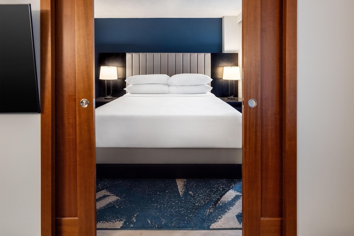 A hotel room with a bed, two bedside lamps, and a blue carpet.
