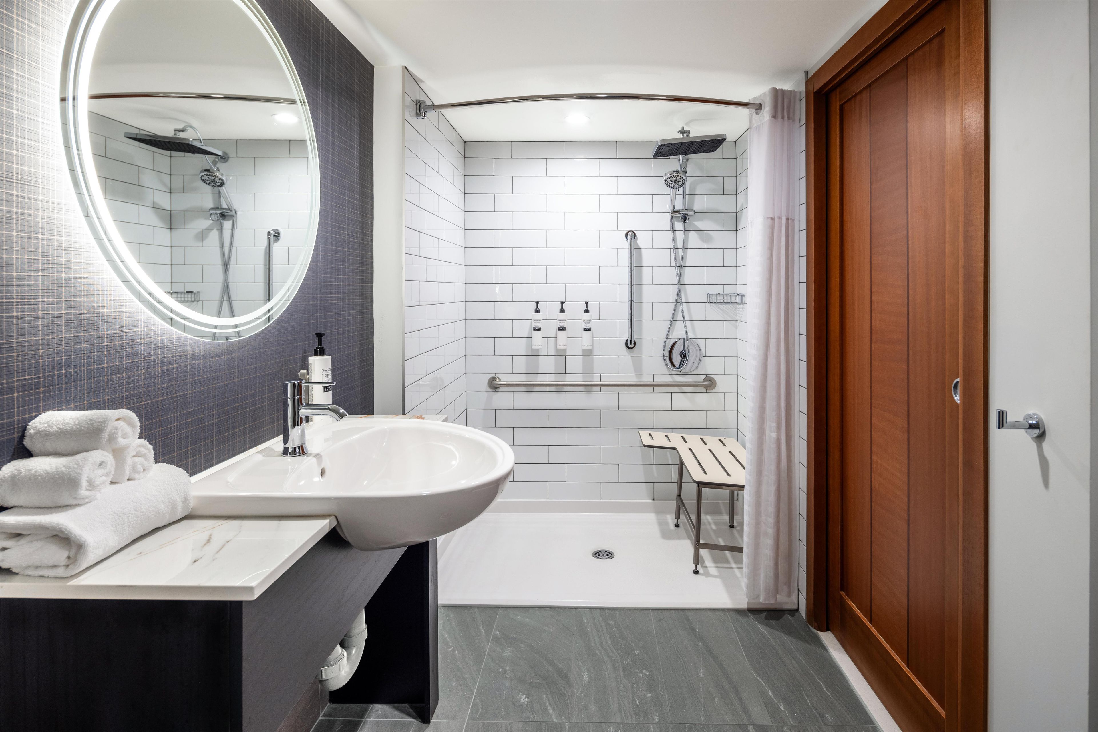 Un baño moderno con un espejo grande, un lavamanos, una ducha y un inodoro.