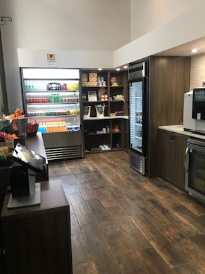 A modern kitchen with a refrigerator, a coffee machine, and a variety of food items on shelves.