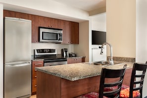 A modern kitchen with a stainless steel refrigerator, a microwave, a stove, and a sink.