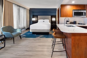 A hotel room with a bed, a desk area with a sink, a microwave, and a coffee machine. - Embassy Suites Montréal by Hilton (Montreal)