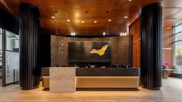 A reception area with a large wall-mounted screen, a reception desk, and a wooden floor.