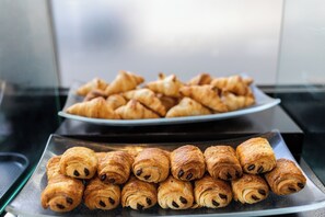 A tray of assorted pastries, including croissants and chocolate-filled rolls, on a glass surface. - Embassy Suites Montréal by Hilton (Montreal)
