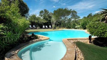 Una piscina al aire libre, sillones reclinables de piscina