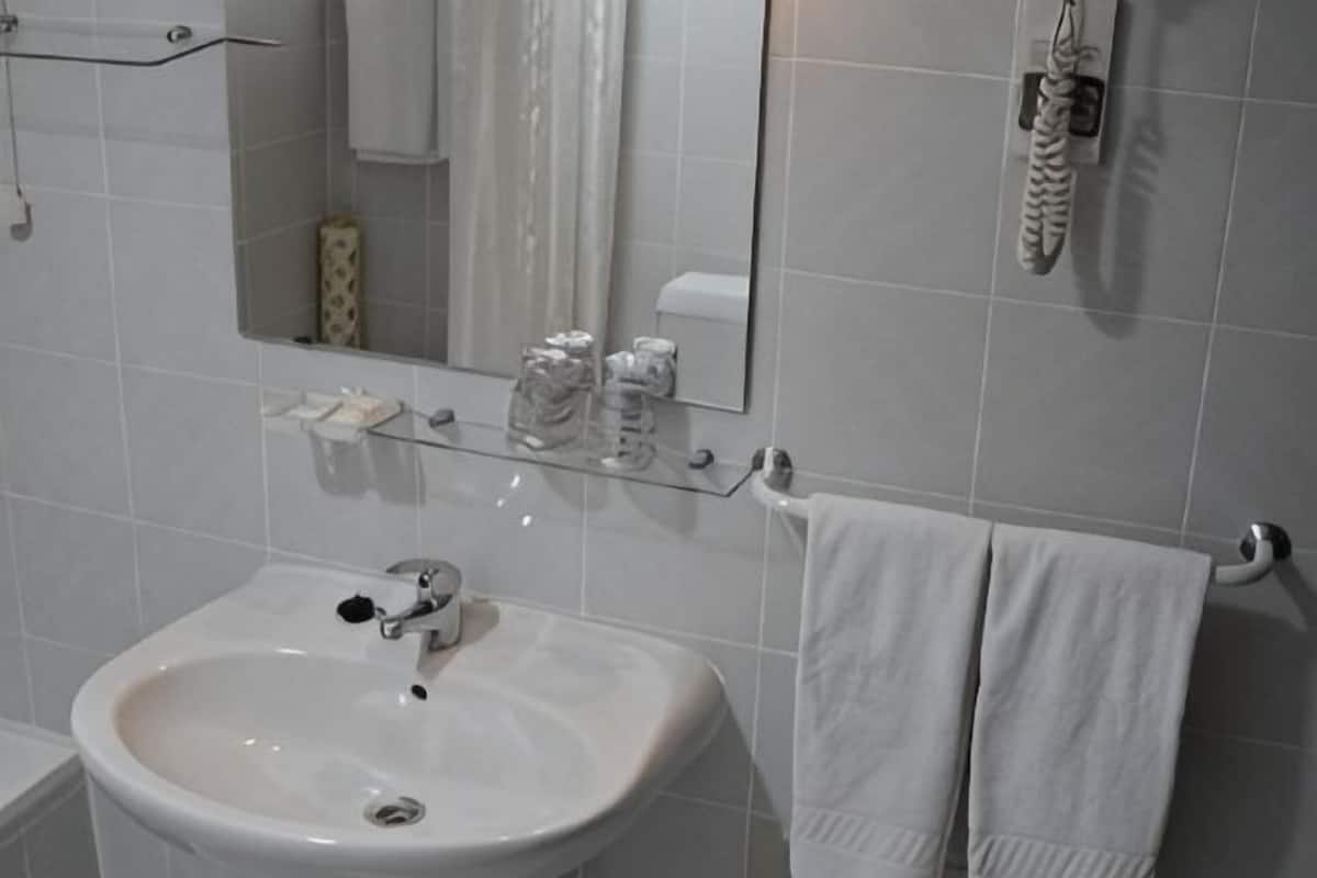 A bathroom with a white sink, mirror, and towel rack.
