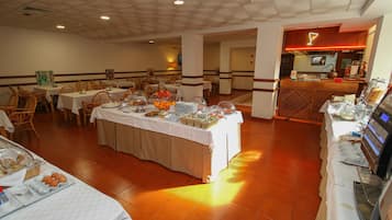 Montaje tipo buffet con mesas, sillas y una zona de exhibición de alimentos en un comedor.