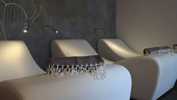 Et moderne spaområde med tre liggestole, hver med et tæppe og en vægmonteret lampe.
