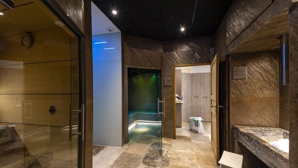 Un baño moderno con cabina de ducha de vidrio, lavamanos de mármol y suelo de baldosas de piedra.
