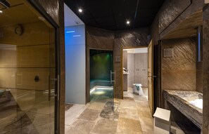 A modern bathroom with a glass shower enclosure, a marble sink, and a stone-tiled floor. - Château de Siran (Siran)