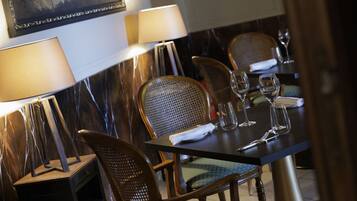 Una mesa de comedor con sillas, una lámpara y copas de vino.