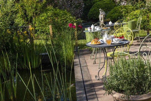 A garden patio with outdoor seating, a statue, and a pond.