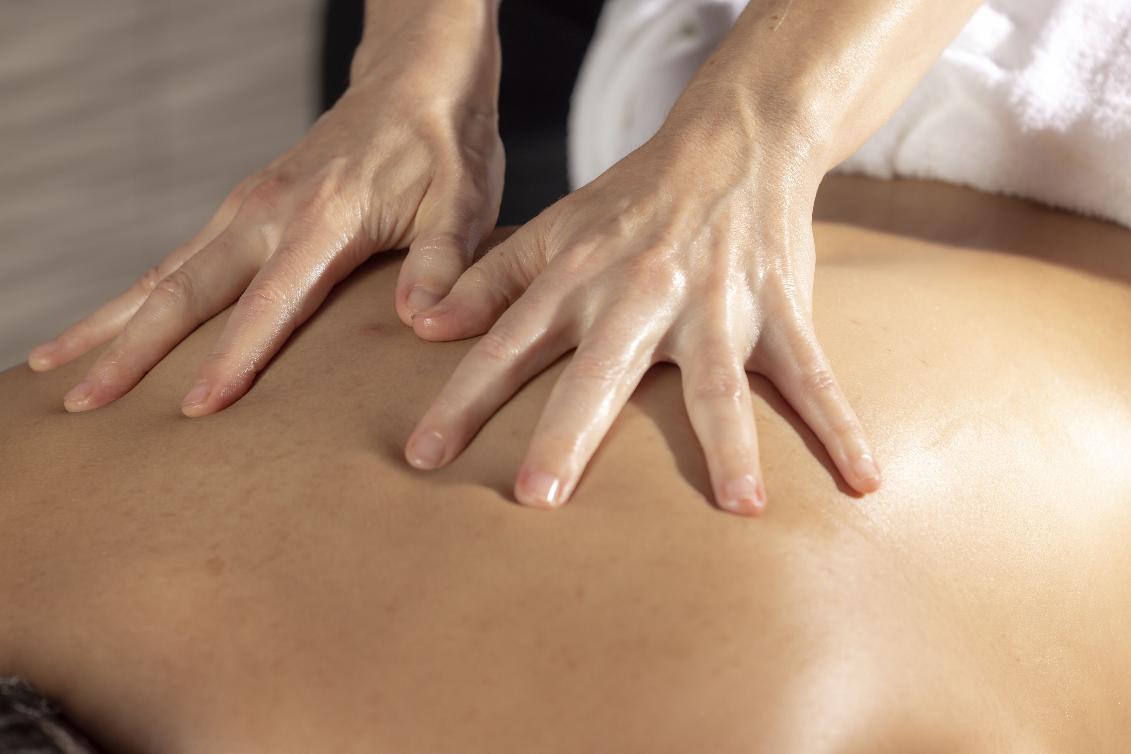 Nahaufnahme von Händen, die eine Rückenmassage geben.