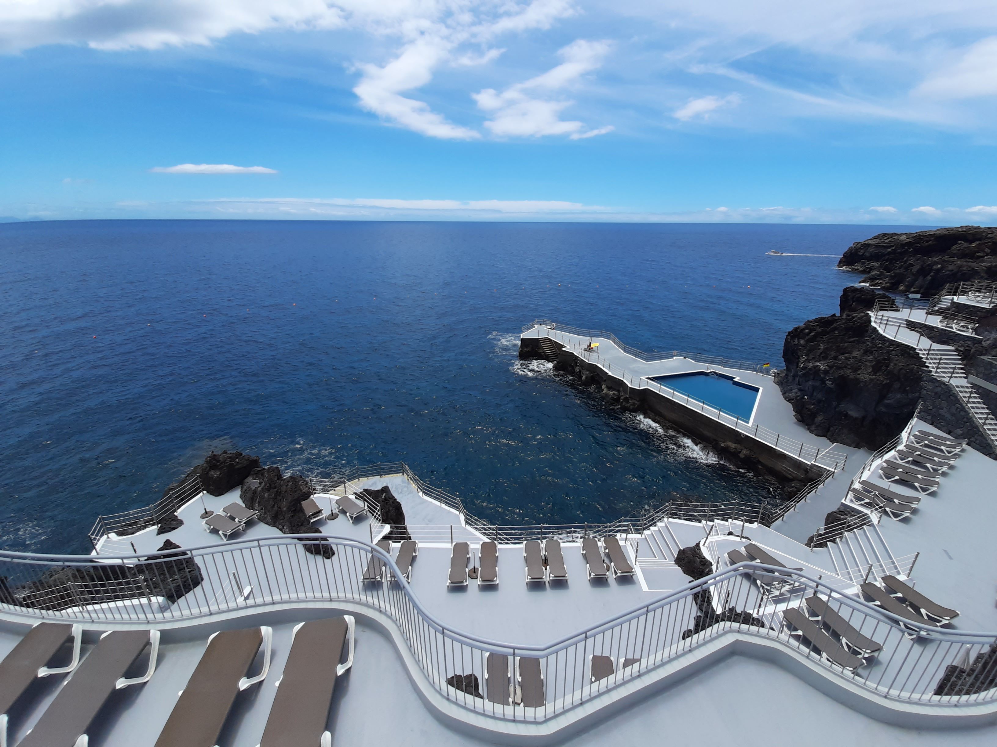 A sun deck with lounge chairs overlooking the ocean.