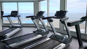 A gym with treadmills and large windows overlooking a body of water. - Royal Orchid (Santa Cruz)