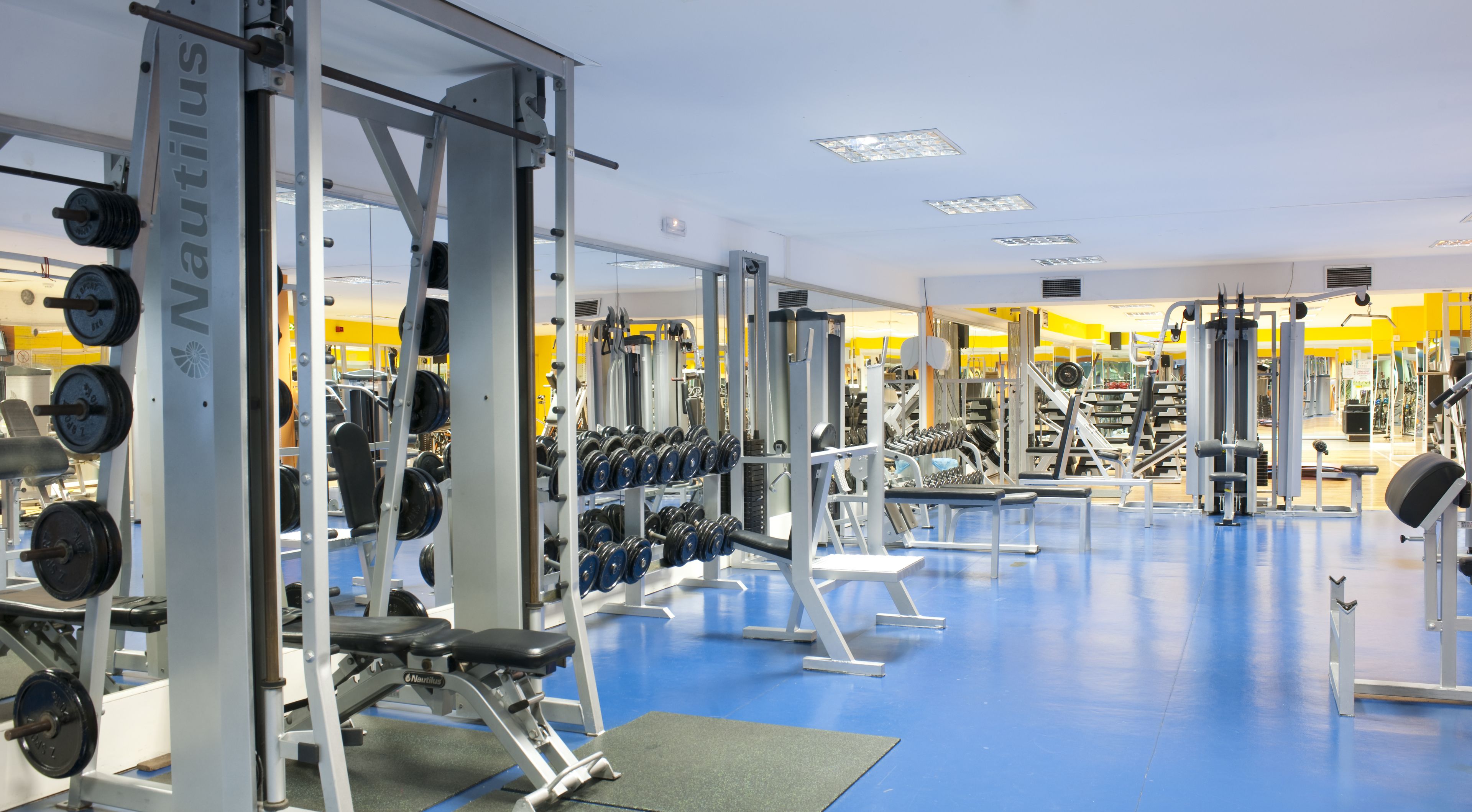 Une salle de sport équipée d’appareils Nautilus, de supports à poids et de bancs.