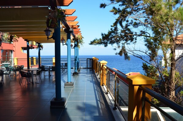Una terraza al aire libre con mesas y sillas, con vistas al mar.
