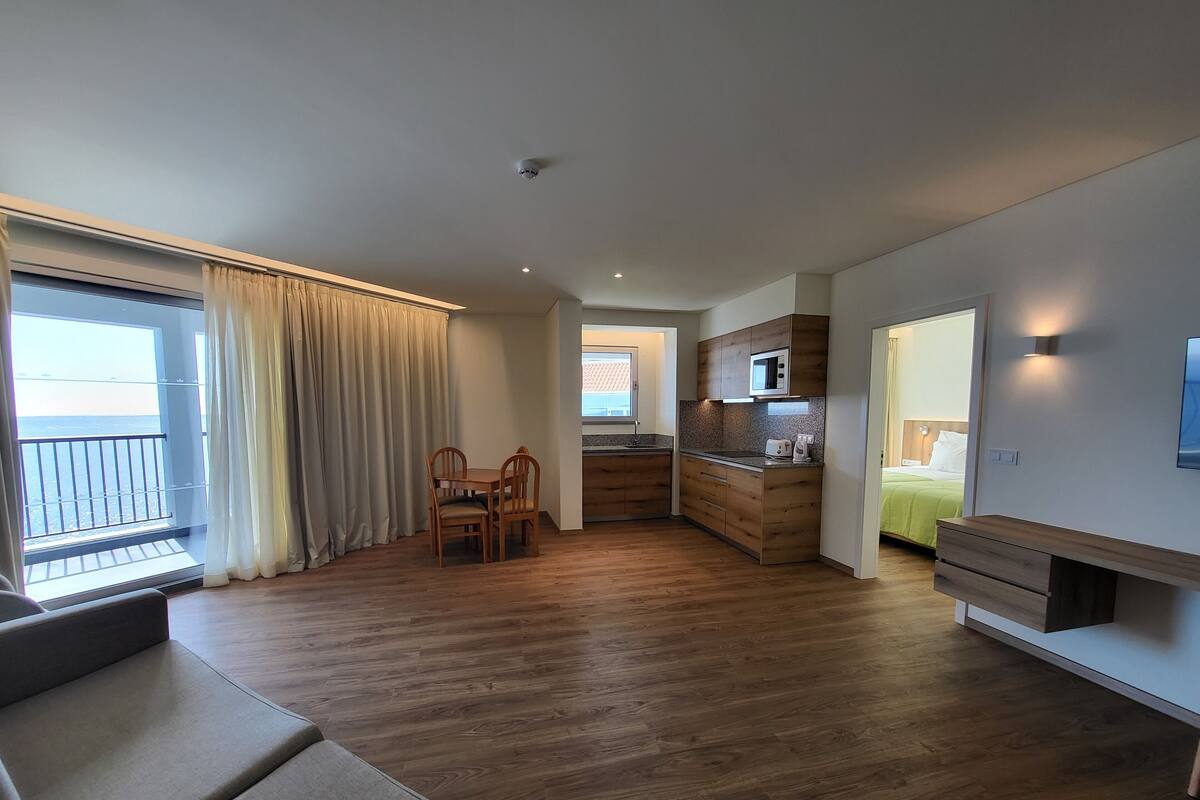 Eine moderne Wohnung mit Essbereich, Küchenzeile und Wohnzimmer mit Sofa.
