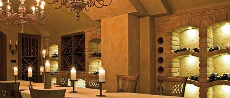 A dining area with a chandelier, wine cellar, and stone walls.